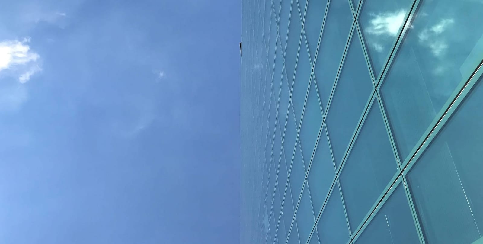 Die Glasfassade eines Hochhauses scheint im blauen Himmel zu verschwimmen