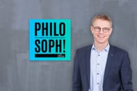 Podcast „Philosoph!“ mit Dr. Gerrit Böhm, im Anzug vor grauer Wand, daneben blaues Logo von Carls Zukunft.